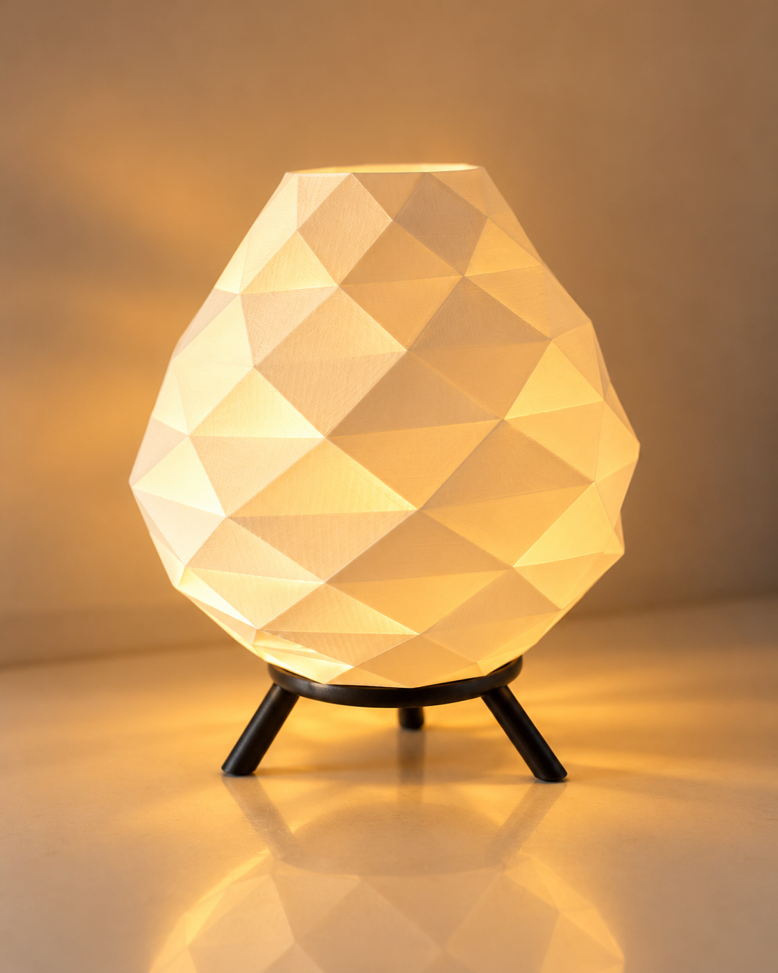 Glowing table lamp with a faceted geometric shade and black tripod base.
