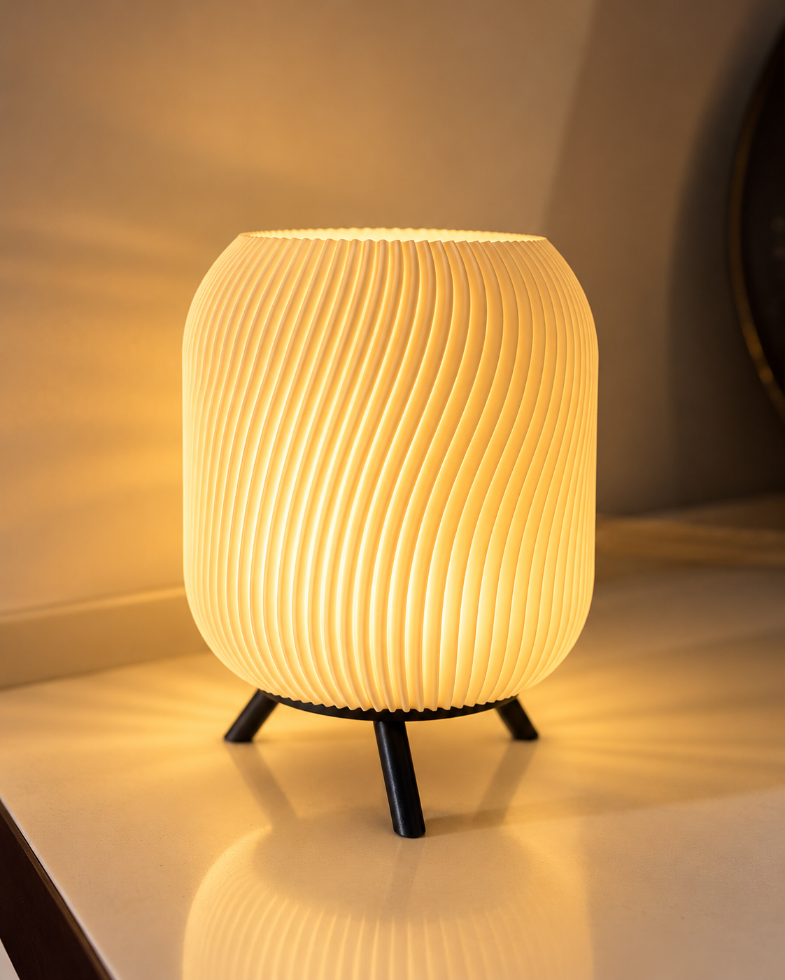 Glowing table lamp with a rounded vertical-ribbed shade and black three-legged base.
